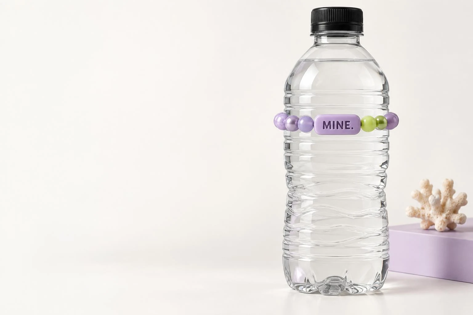 A clear water bottle wearing a lilac band with an embossed MINE. tile and small lime accent zone